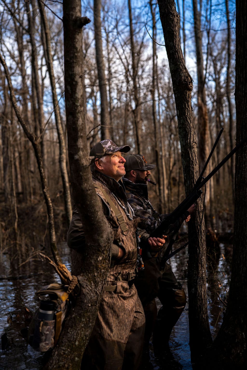 Two hunters in a forested area.