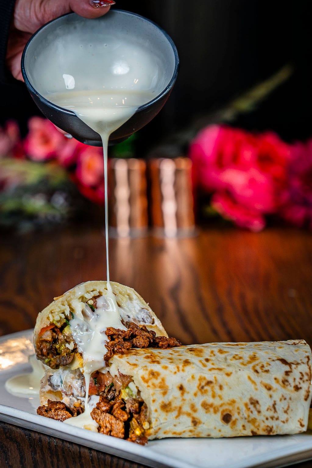 Burrito with cheese sauce pouring