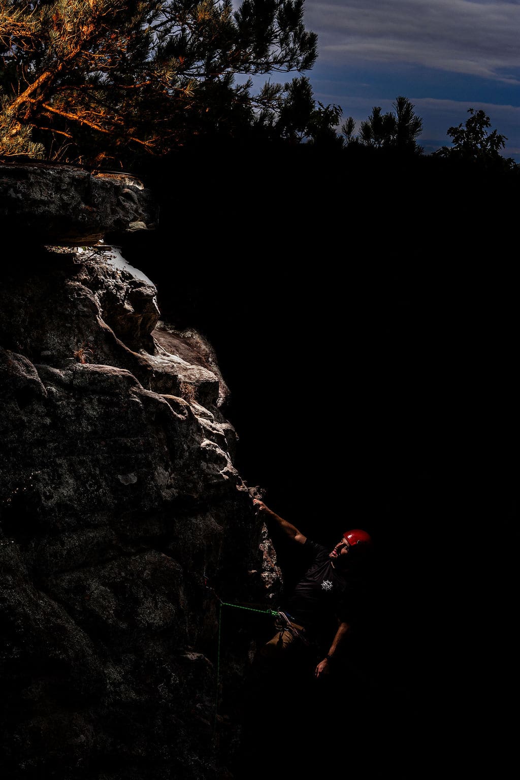 Climber scaling a dark rock face.
