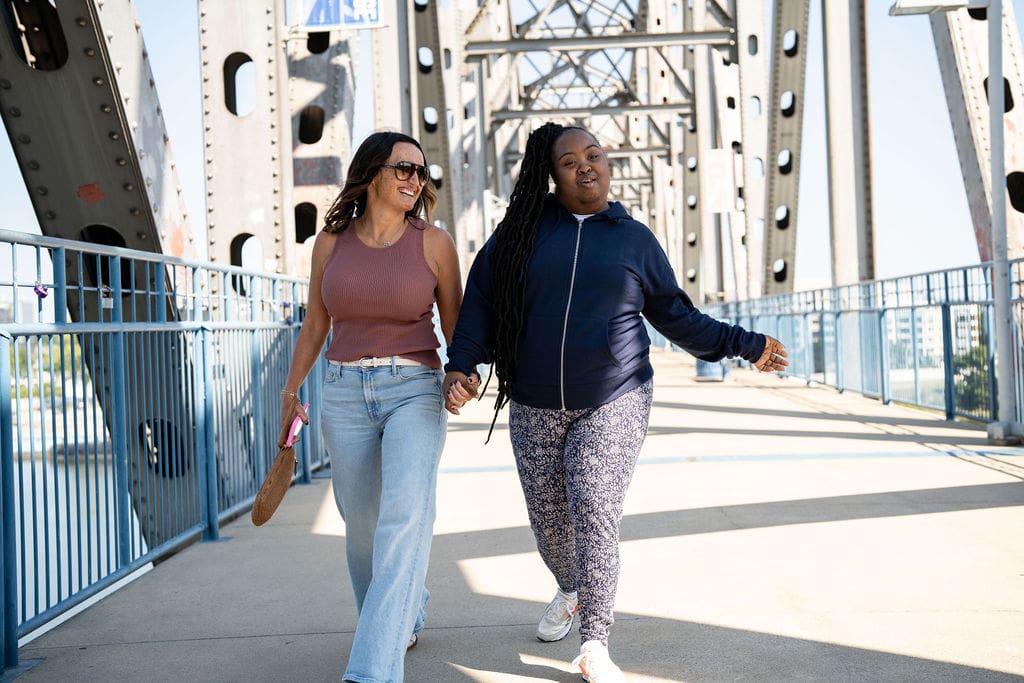 Two women walking hand in hand.